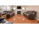 Cozy living room showcasing a fireplace, TV, and comfortable leather sofas on gleaming hardwood floors at 128 Lacona Trce, Mooresville, NC 28115