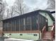 A screened porch with a brown wood frame is attached to a home with green siding and a gray sky above at 152 Muskhogean Way, Mount Gilead, NC 27306
