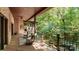 Inviting back porch with seating and views of the surrounding trees, landscaping, and running stream at 225 Riverton Rd, Weddington, NC 28104
