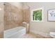 Bright bathroom featuring a bathtub with tile surround and a window offering a serene view of the outdoors at 225 Riverton Rd, Weddington, NC 28104