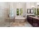 Luxurious bathroom with glass shower, soaking tub, granite countertops, and natural light from large window at 225 Riverton Rd, Weddington, NC 28104