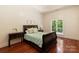 Bedroom with green accents, bedside table, and hardwood floors overlooking natural lighting from large window at 225 Riverton Rd, Weddington, NC 28104