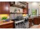 Close-up of the kitchen with stainless steel oven, cooktop, stone hood, custom cabinetry, and granite countertops at 225 Riverton Rd, Weddington, NC 28104
