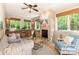 Cozy living room with a stone fireplace, built-in cabinets, and large windows offering picturesque outdoor views at 225 Riverton Rd, Weddington, NC 28104