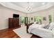 Main bedroom with en-suite bathroom access, TV, dresser, exterior access, and wooded views at 225 Riverton Rd, Weddington, NC 28104