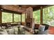 Cozy sunroom featuring a brick fireplace, wood ceiling, and screened windows overlooking a wooded area at 225 Riverton Rd, Weddington, NC 28104