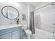 Clean bathroom featuring a vanity with grey cabinets, a round mirror, and a combined bathtub and shower at 3288 Sherman Dr, Lancaster, SC 29720