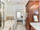 A spacious bathroom with a tub, wood cabinets, tile floors, and a doorway to a bedroom at 8925 Rosalyn Glen Rd, Cornelius, NC 28031