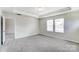 Bedroom featuring neutral carpet, tray ceiling, and two windows with horizontal blinds at 12241 Gambrell Dr, Charlotte, NC 28278