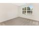 Bright, carpeted bedroom with a large window overlooking a quiet street at 8465 Old Plank Rd, Charlotte, NC 28216