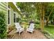 Backyard brick patio with comfortable white Adirondack chairs and lush green landscaping at 10213 Conistan Pl, Cornelius, NC 28031