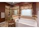 A relaxing soaking tub with a decorative window and a separate glass-enclosed shower create a spa-like bathroom at 15309 Guthrie Dr, Huntersville, NC 28078