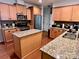 Spacious kitchen featuring stainless steel appliances, granite countertops, kitchen island, wood cabinets and hardwood floors at 1726 Still River Way, Fort Mill, SC 29708