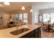 Kitchen island with sink, light countertop and dark wood cabinetry; adjacent to dining area at 3156 Pinehills Way, Mount Holly, NC 28120