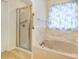 Bathtub and standup shower featuring beige tile, glass doors, and a blue patterned curtain at 340 Tradewinds Ln, York, SC 29745