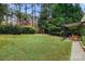 Large backyard with a covered patio area, lush green grass, and mature trees at 3419 Wylie Meadow Ln, Charlotte, NC 28269