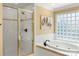 Bright bathroom features a tiled shower with gold trim and relaxing tub with glass block window at 3419 Wylie Meadow Ln, Charlotte, NC 28269