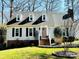 Charming home with a well-manicured lawn, brick foundation, dormer windows, and a welcoming pink front door at 6525 Castlegate Dr, Charlotte, NC 28226