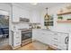 Bright, modern kitchen with white cabinets, stainless steel appliances, quartz countertops, and wooden floating shelves at 6525 Castlegate Dr, Charlotte, NC 28226