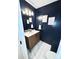 Stylish powder room with a wood vanity, modern fixtures, marble floors, and blue walls at 6525 Castlegate Dr, Charlotte, NC 28226