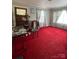 Living room featuring a red carpet, neutral walls, and two windows with patterned curtains at 708 Mount Olive Church Rd, Newton, NC 28658
