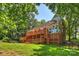 A lush backyard featuring a spacious wooden deck and a play structure, surrounded by mature trees at 8000 Greencastle Dr, Charlotte, NC 28210