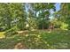 Spacious backyard offers lush lawn, mature trees, and a charming wooden playhouse with swings for outdoor enjoyment at 8000 Greencastle Dr, Charlotte, NC 28210