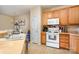 Practical kitchen featuring wood cabinets, white appliances, and tile flooring at 8460 Summerglen Cir, Charlotte, NC 28227