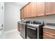 Well-organized laundry room with granite countertops, wooden cabinets, modern washer, and dryer units at 22030 Molly Harper Dr, Cornelius, NC 28031