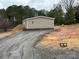 Single-story home featuring neutral siding, a wooden staircase, and a gravel driveway surrounded by mature trees at 238 Fairchase Cir # 54, Stony Point, NC 28678