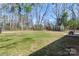 Spacious backyard with green grass and trees, featuring a storage shed and patio with table at 2537 Wood Star Ct, Matthews, NC 28215