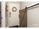 Close-up of the entryway's white front door with wreath and rustic sliding barn door at 3216 Bridgewick Rd, Waxhaw, NC 28173