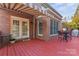 Inviting back porch featuring a red deck, brick exterior, and outdoor seating at 4608 Snow Dr, Harrisburg, NC 28075