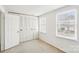 Bedroom featuring neutral carpet, two windows, and a closet with folding doors at 7344 Pebblestone Dr # E, Charlotte, NC 28212