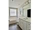 This bathroom features a white vanity, white toilet, and white bathtub with a window at 7702 Brisbane Ct, Charlotte, NC 28215