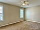 This bedroom features neutral paint, carpet flooring, bright windows and a ceiling fan at 7702 Brisbane Ct, Charlotte, NC 28215