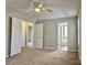 This bedroom features neutral paint, carpet flooring, bright windows, ceiling fan, and multiple doorways at 7702 Brisbane Ct, Charlotte, NC 28215