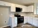Modern kitchen featuring stainless steel appliances, white cabinets, and quartz countertops at 7702 Brisbane Ct, Charlotte, NC 28215