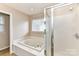Bright bathroom featuring a bathtub with tile flooring, shower, and neutral paint at 7713 Dunoon Ln, Charlotte, NC 28269