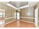 Formal dining room with elegant chandelier, wainscoting, tray ceiling, and hardwood floors at 7713 Dunoon Ln, Charlotte, NC 28269