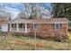 Classic brick home with attached garage, a covered front porch and mature trees at 821 Cabaniss Dr, Shelby, NC 28150