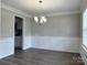 Dining room with hardwood floors, grey walls, wainscoting, crown molding, chandelier, and window at 8812 Glenover Cir, Charlotte, NC 28269