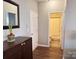 Inviting hallway featuring wood floors, a stylish mirror, and an entrance to a well-lit bathroom at 14809 Castletown House Dr, Charlotte, NC 28273