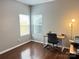 Bright home office featuring hardwood floors, natural light from two windows, and a modern desk setup at 14809 Castletown House Dr, Charlotte, NC 28273