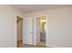 Neutral hallway featuring white doors, light walls, and wood floors, leading to an open bathroom and staircase at 3924 Craig Ave, Charlotte, NC 28211