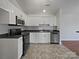 Well-lit kitchen with white cabinetry, stainless steel appliances, and dark countertops at 414 Fox Fire Run, Gastonia, NC 28052