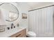 Bright bathroom features a modern vanity, round mirror, and shower with a curtain at 5120 Silabert Ave, Charlotte, NC 28205