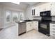 Traditional kitchen featuring white cabinets, black appliances, and a bay window overlooking a deck at 7007 Chapparall Ln, Charlotte, NC 28215