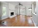 Bright living room features hardwood floors, a painted brick fireplace, large windows, and neutral decor at 7007 Chapparall Ln, Charlotte, NC 28215