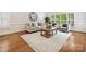 Living room with hardwood floors, neutral furniture, large windows, and area rug at 7329 Kennington Ct, Charlotte, NC 28270